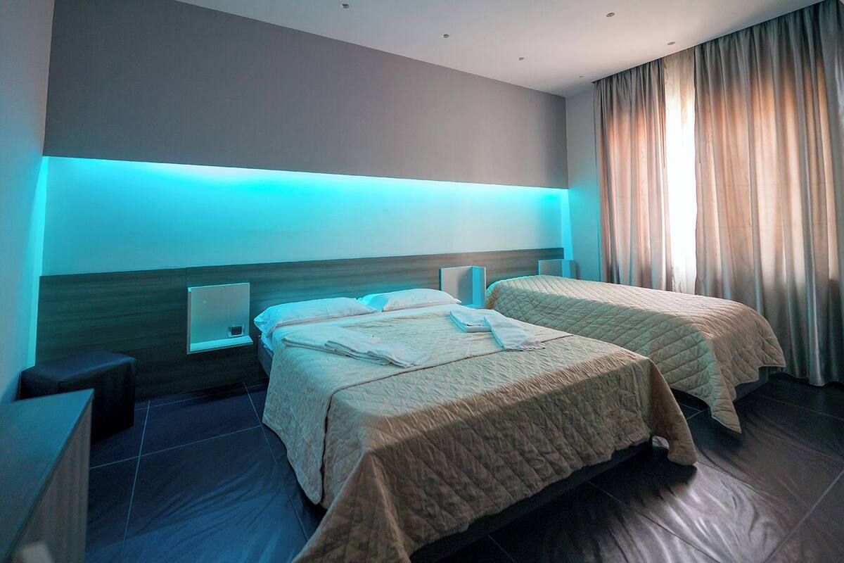 A hotel room with two beds, a nightstand, and a desk.
