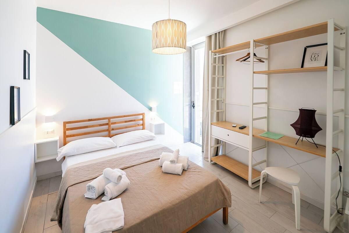 A bedroom with a bed, bedside tables, a desk, a chair, and a wardrobe.