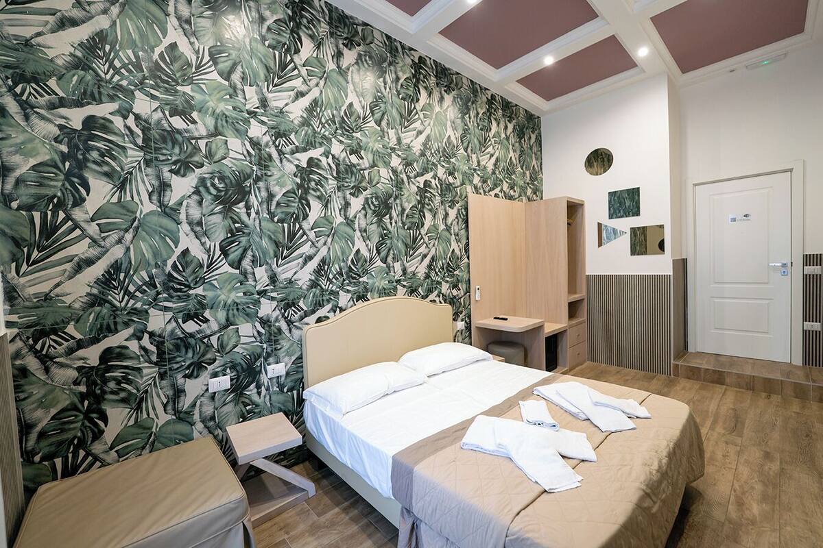 A hotel room with a bed, a desk, a wardrobe, and a shower area.