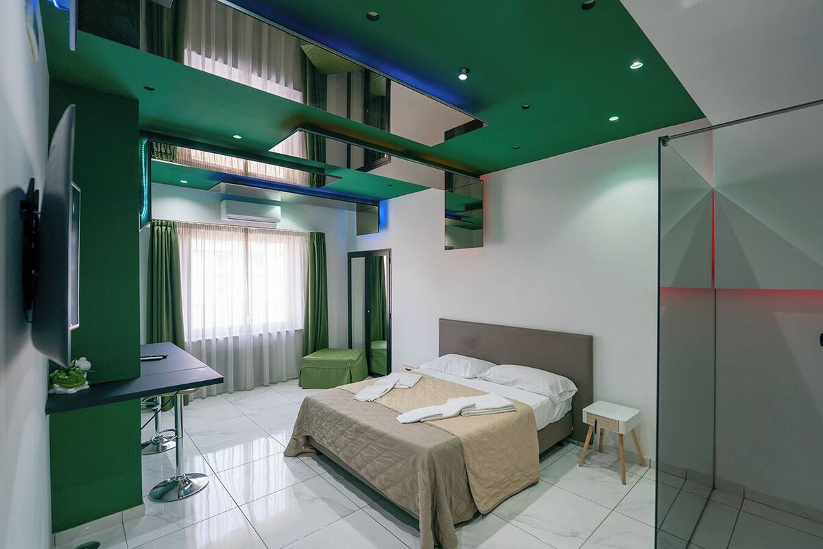 A modern bedroom with a bed, a desk, and a TV.