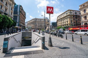 Eine Stadtstraße mit historischen Gebäuden, einer Bushaltestelle und einem Eingang zur U-Bahn.