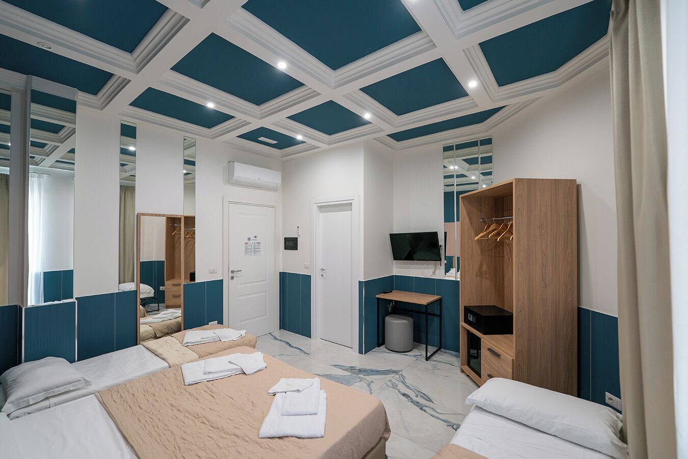 A hotel room with a bed, a desk, a TV, and a wardrobe.