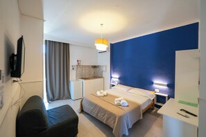 Ein Hotelzimmer mit Bett, Nachttisch, Schreibtisch und einer Küchenzeile.