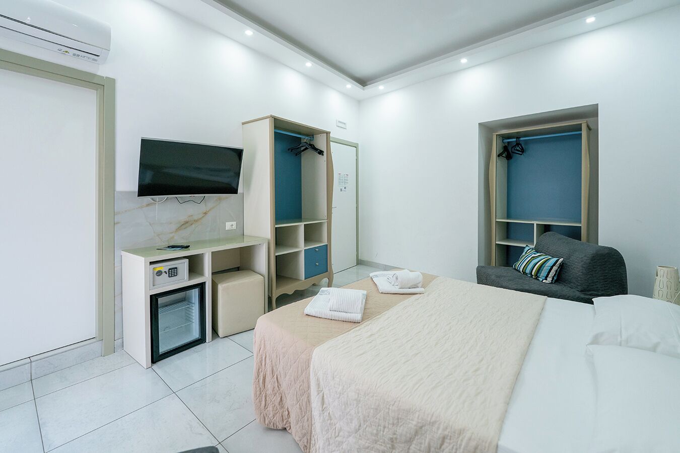 Une chambre moderne équipée d’un lit, d’un bureau, d’une télévision et d’une armoire.