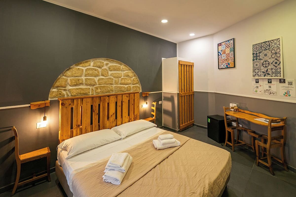 A bedroom with a stone headboard, a wooden desk, and a chair.