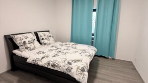 A bedroom with a bed, a window with curtains, and a ceiling light.