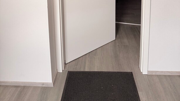 A doorway leading to a kitchen with a red countertop and a white door.