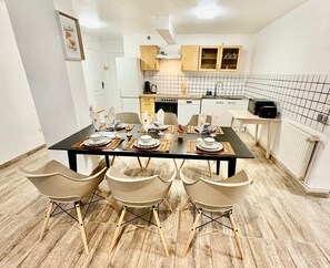 A modern kitchen with white cabinets, a black countertop, and a dining table set for four. - The Kampmann – Spacious apartment in Strasbourg (Strasbourg)