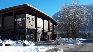 Un cine con fachada de madera y señalización, rodeado de nieve en el suelo y árboles.