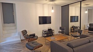 Una sala de estar moderna con un sofá, sillones, una mesa de centro y un televisor.