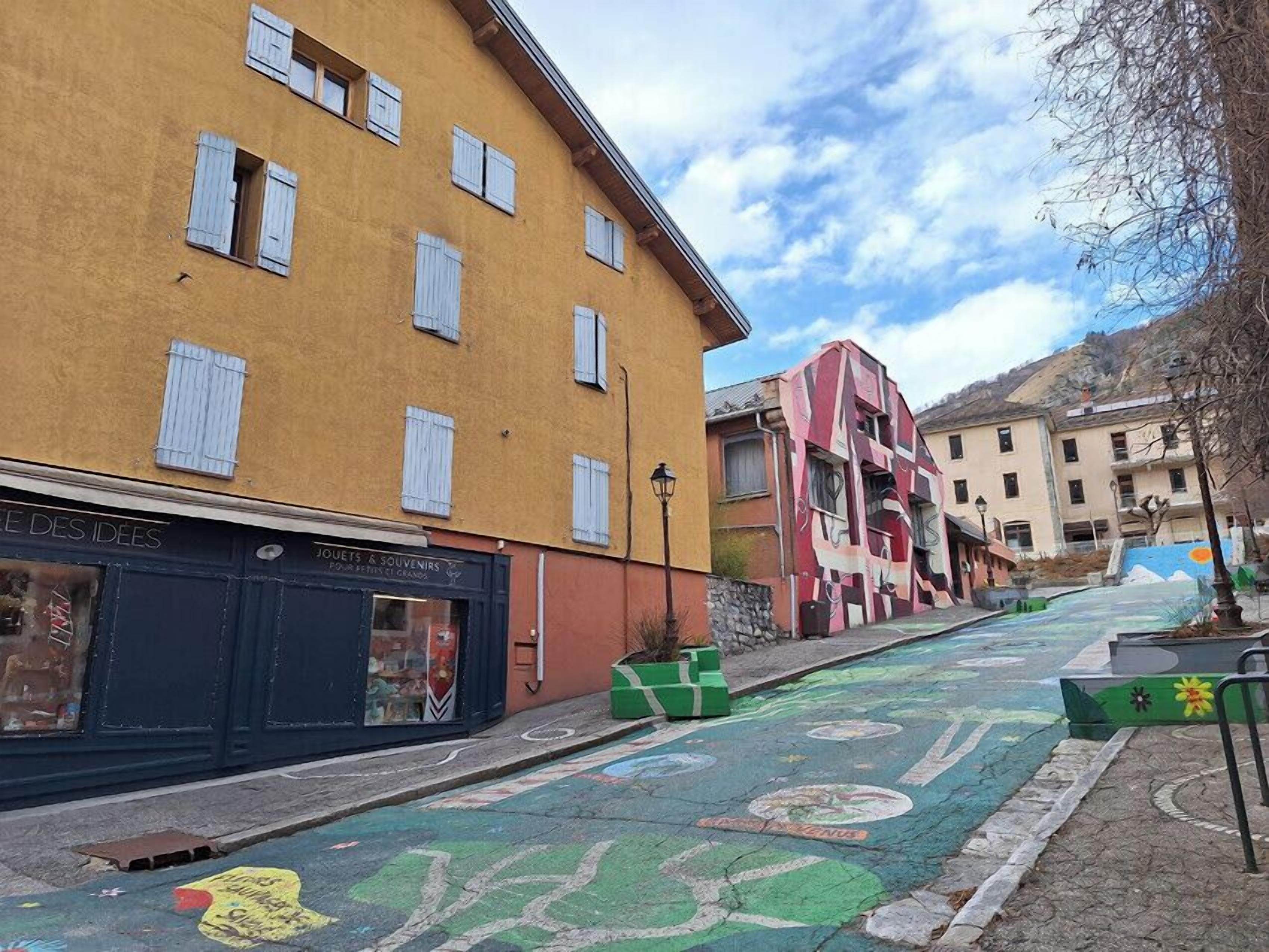 Una calle con edificios coloridos, un carril bici y una pequeña zona arbolada.