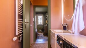 A laundry area with a washing machine and dryer, a mirror, and a towel hanging on the wall. - SquareView Apartment (Prishtina)