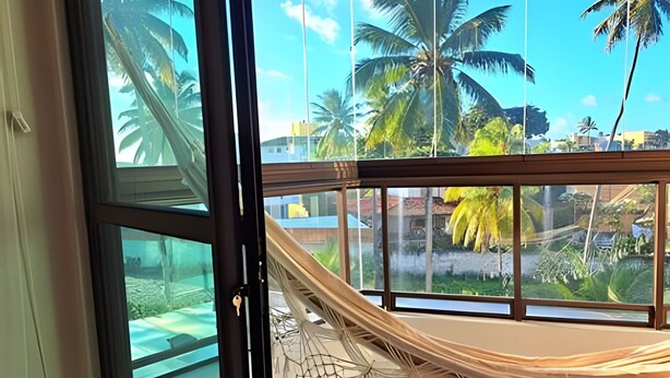 A room with a large window, a hammock, and a view of palm trees and a water feature outside. - Aloha Residence (Ipojuca)