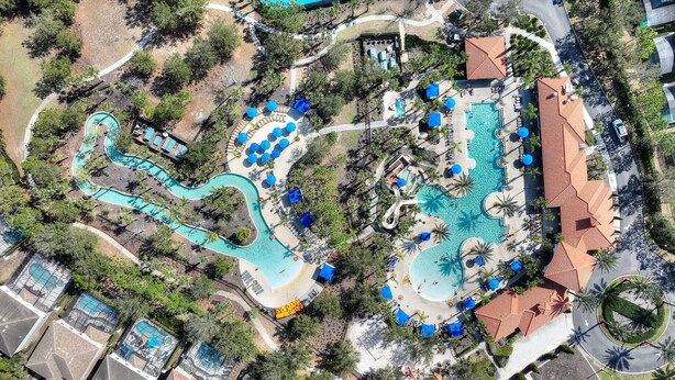 An aerial view of a resort with multiple swimming pools, sun loungers, and palm trees. - 25% Off Luxury Disney Retreat in Solterra (Davenport)