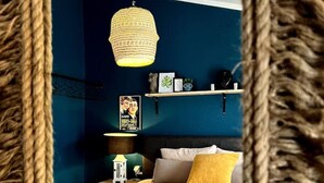 Ein Schlafzimmer mit einem Bett, einer Hängelampe, einem Nachttisch und einem an der Wand befestigten Regal.