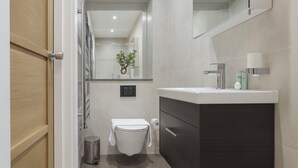 Ein modernes Badezimmer mit Toilette, Waschbecken und Spiegel.