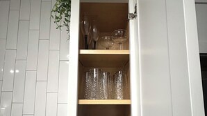 A kitchen with a white cabinet containing glassware and a basket.