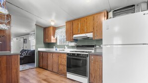 Une cuisine avec des meubles de rangement en bois, un réfrigérateur blanc, une cuisinière et un four à micro-ondes.