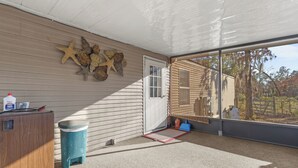 Un porche abrité avec une armoire en bois, une poubelle et une décoration en forme d’étoile de mer.