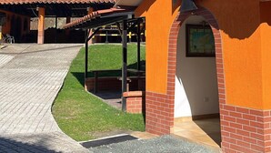 A building with a red-tiled roof, a brick lower section, and a covered outdoor area with a bench. - HOTEL CAFELIA BOUTIQUE (Pereira)