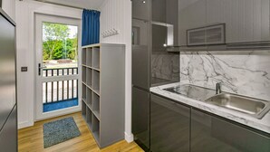 Et moderne køkken med lysegrå skabe, en marmorbordplade og en stålvask.