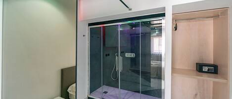 Een moderne badkamer met een douchecabine van glas, een klein nachtkastje en een houten plank.