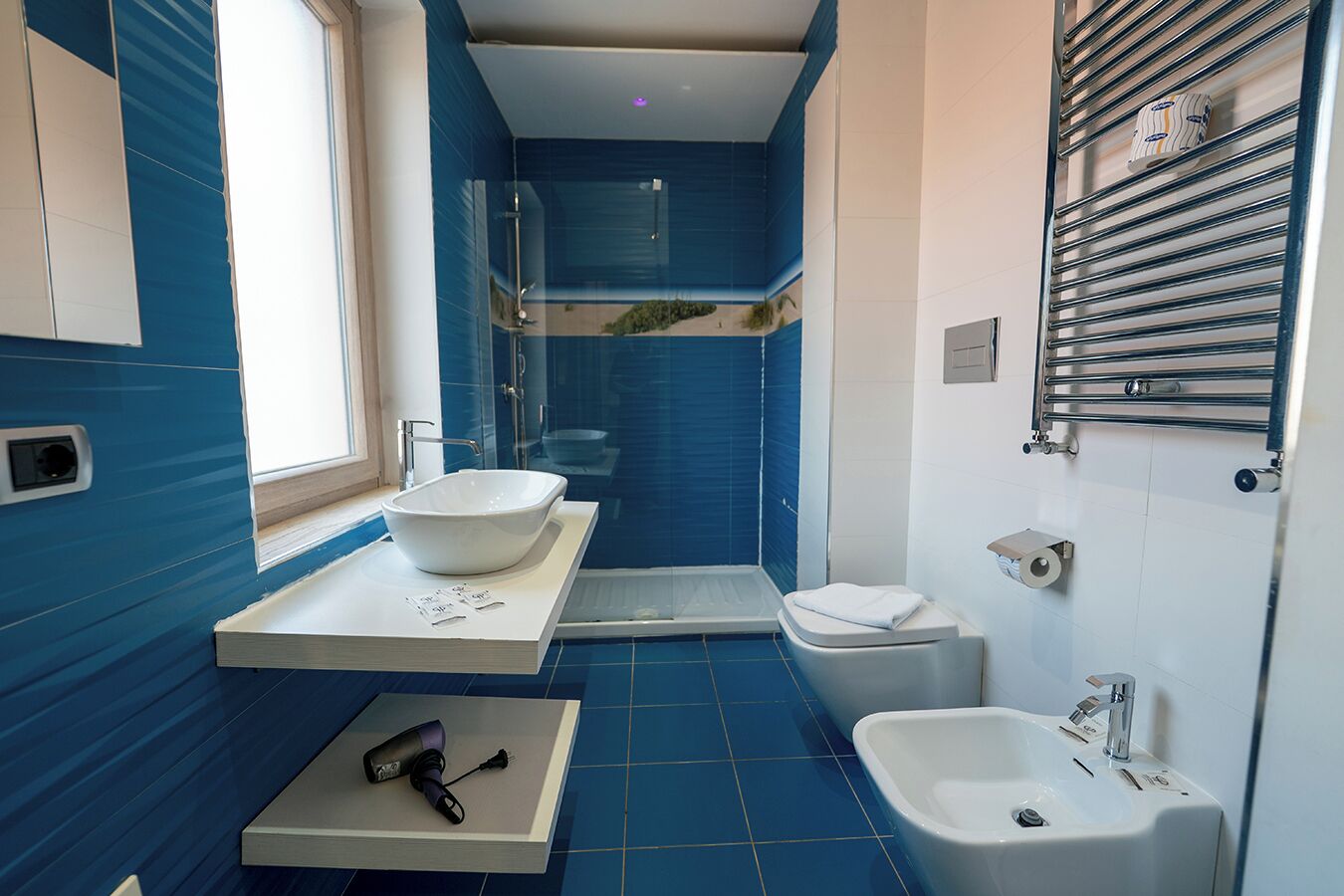 A modern bathroom with a large sink, a shower, and a bidet.