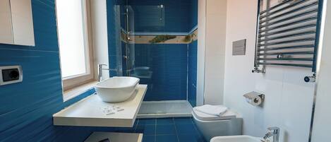 A modern bathroom with a large sink, a shower, and a bidet.