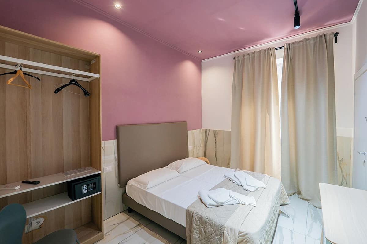 A bedroom with a bed, a desk, and a wardrobe.