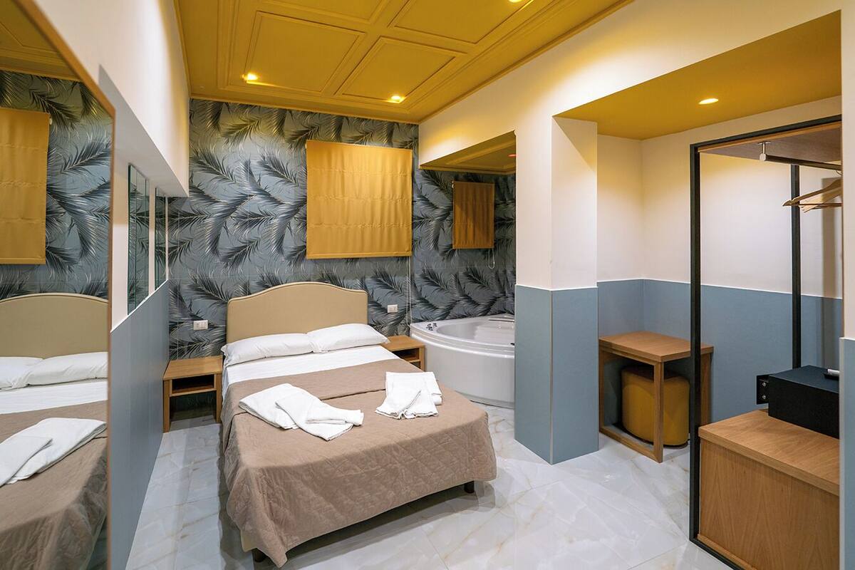 A hotel room with a bed, a bathtub, a wooden cabinet, and a mirror.