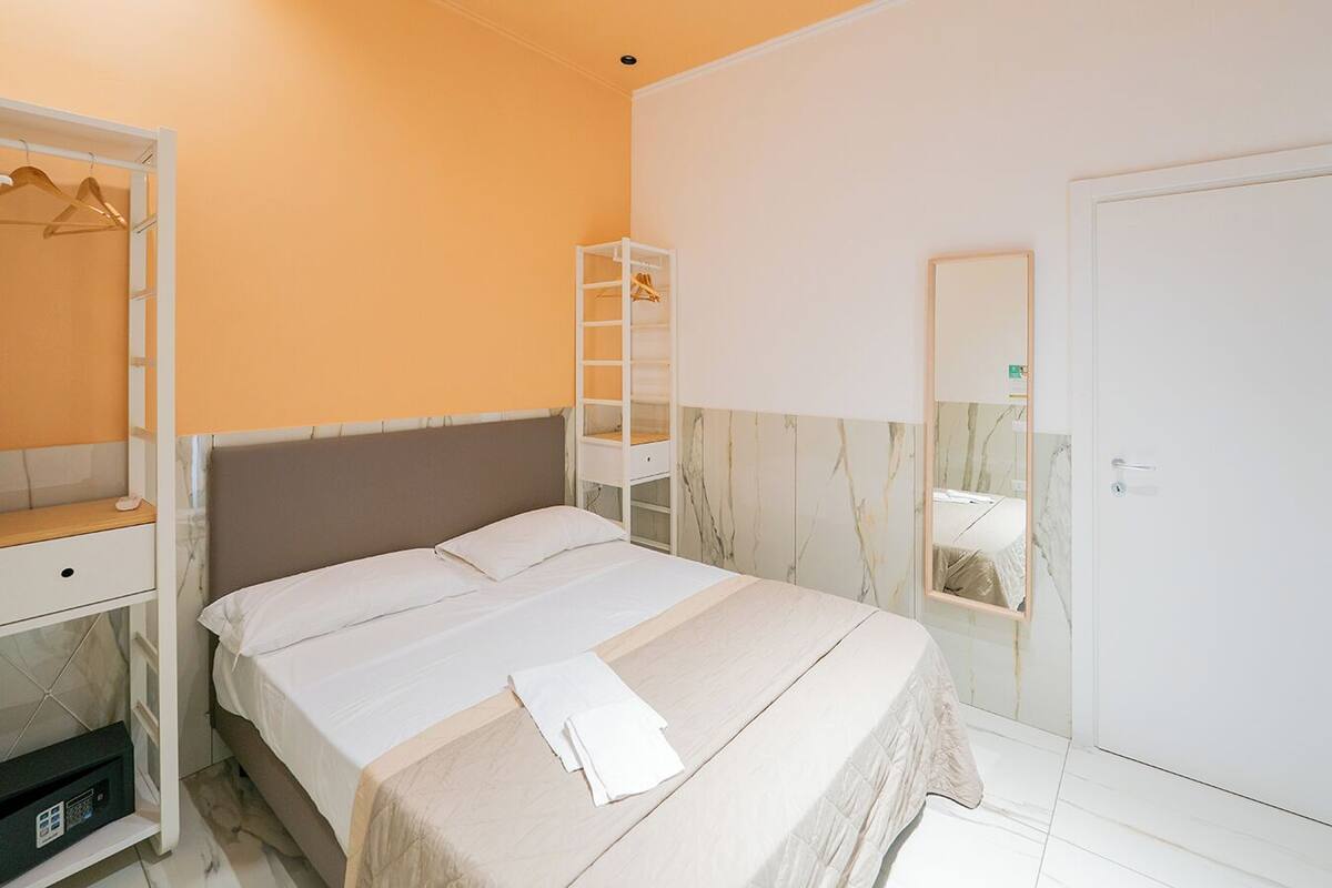 A bedroom with a bed, a wardrobe, a mirror, and a door.