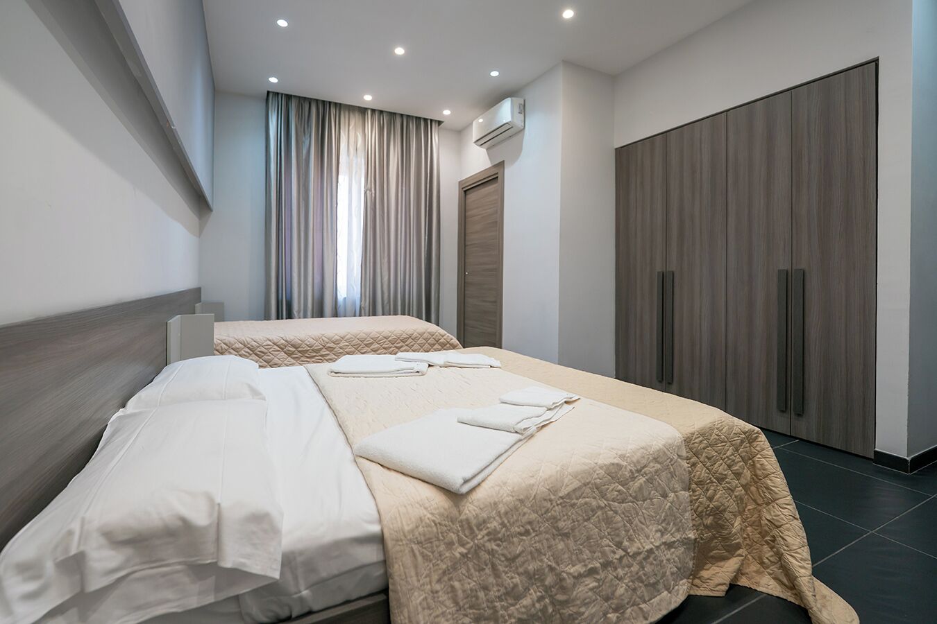 Et moderne hotelværelse med to senge, et stort klædeskab og en aircondition.