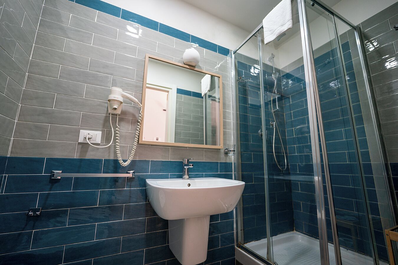 Un baño con un lavabo blanco, un espejo y cabina de ducha con paredes de vidrio.