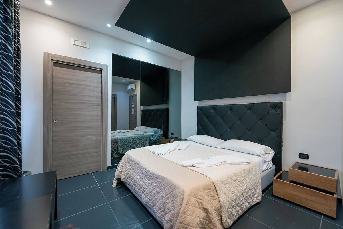 A modern bedroom with a large bed, a wardrobe, and a built-in TV.