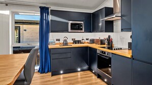 A modern kitchen with dark cabinetry, a wooden countertop, and a built-in microwave. - Silverwood Premium Chalet (Errol)