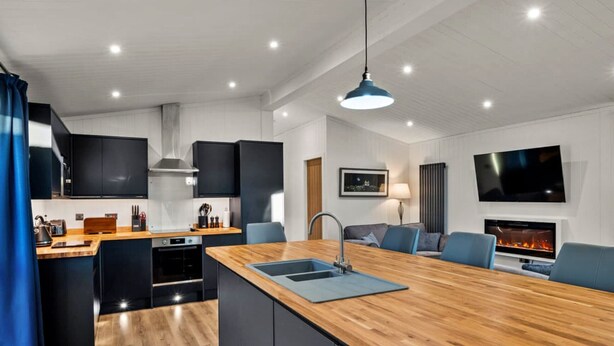 A modern kitchen with a central island, black cabinets, and a wooden countertop. - Silverwood Premium Chalet (Errol)