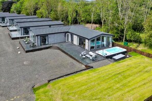 Ein modernes Haus mit Swimmingpool, mehreren Zimmern und einem gepflegten Rasen.