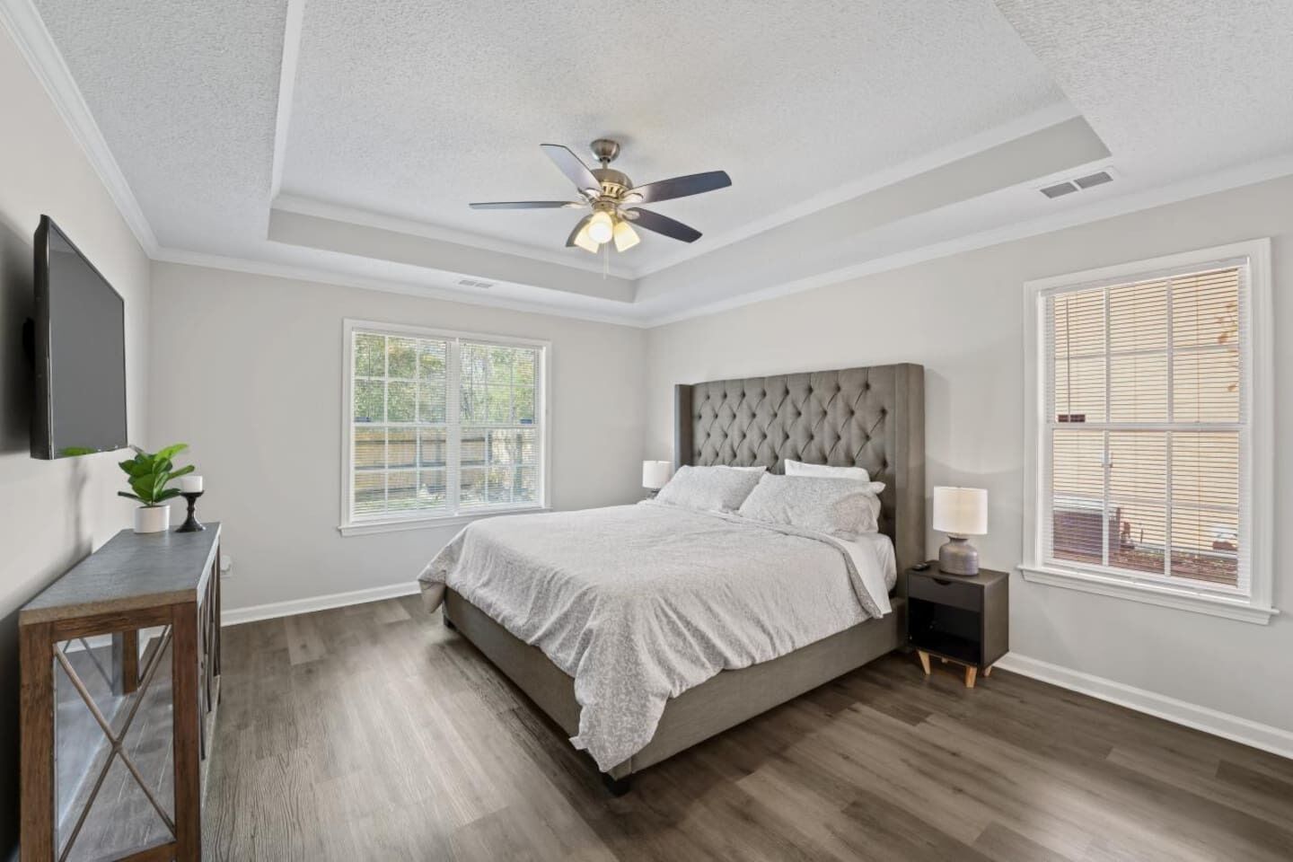 A bedroom with a large bed, a ceiling fan, and a window with blinds.