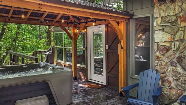 Een houten terras met een jacuzzi, een stenen muur en een blauwe Adirondack-stoel.