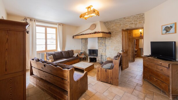 Un salon chaleureux avec une cheminée en pierre, des meubles en bois et un téléviseur.