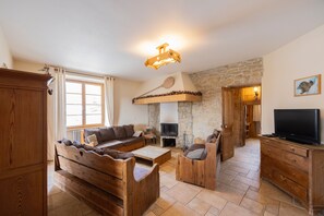 Una sala de estar acogedora con chimenea de piedra, muebles de madera y un televisor.