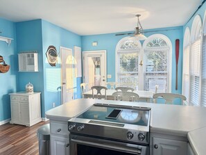 A kitchen with a stainless steel stove, white cabinetry, and a dining area with a table and chairs. - Sandy Sound- Half house, BoatDock, 2 min walk to beach, Hot tub, Sleeps 8, Views (Emerald Isle)