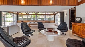 Un vaste espace de vie comprenant une table basse centrale, des fauteuils en cuir et un meuble en bois.