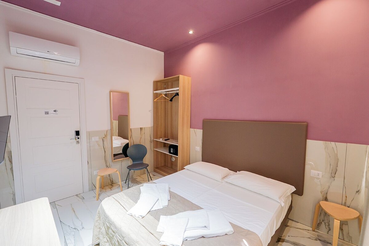 A modern bedroom with a bed, a wardrobe, a mirror, and a small desk.