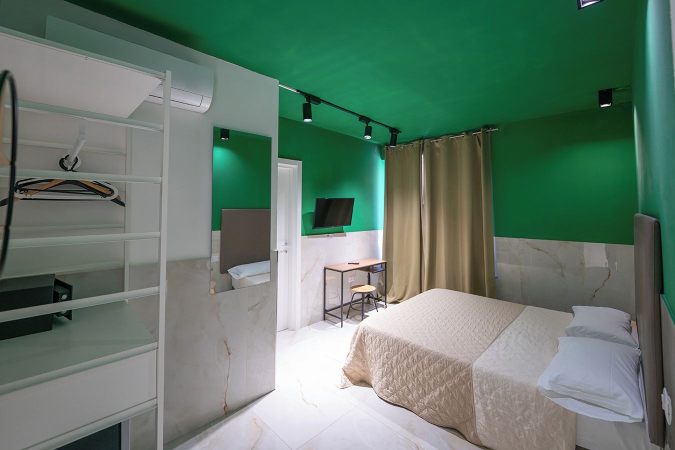A hotel room with a bed, a desk, a chair, a TV, and a wardrobe.
