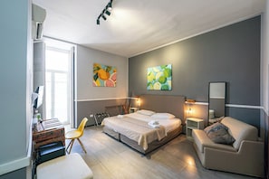 A modern bedroom with a bed, bedside tables, a chair, and artwork on the walls. - GREROS DANTE H. by Clapa Group dislocated hospitality (Naples)