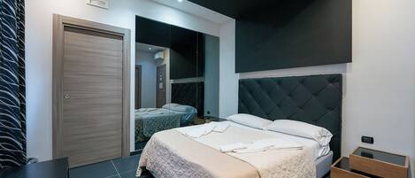 A modern bedroom with a large bed, a wardrobe, and a mirror.