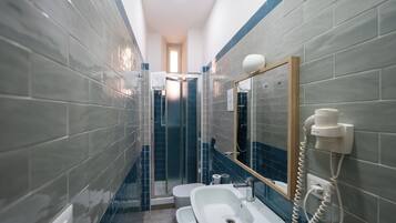 A narrow bathroom with a sink, mirror, and a telephone.