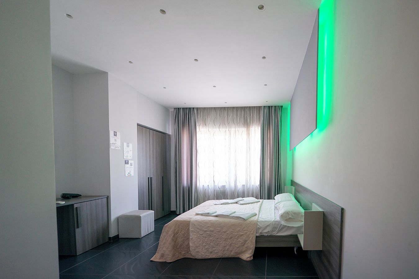 Ein modernes Hotelzimmer mit Bett, Nachttisch und Schreibtisch mit Stuhl.
