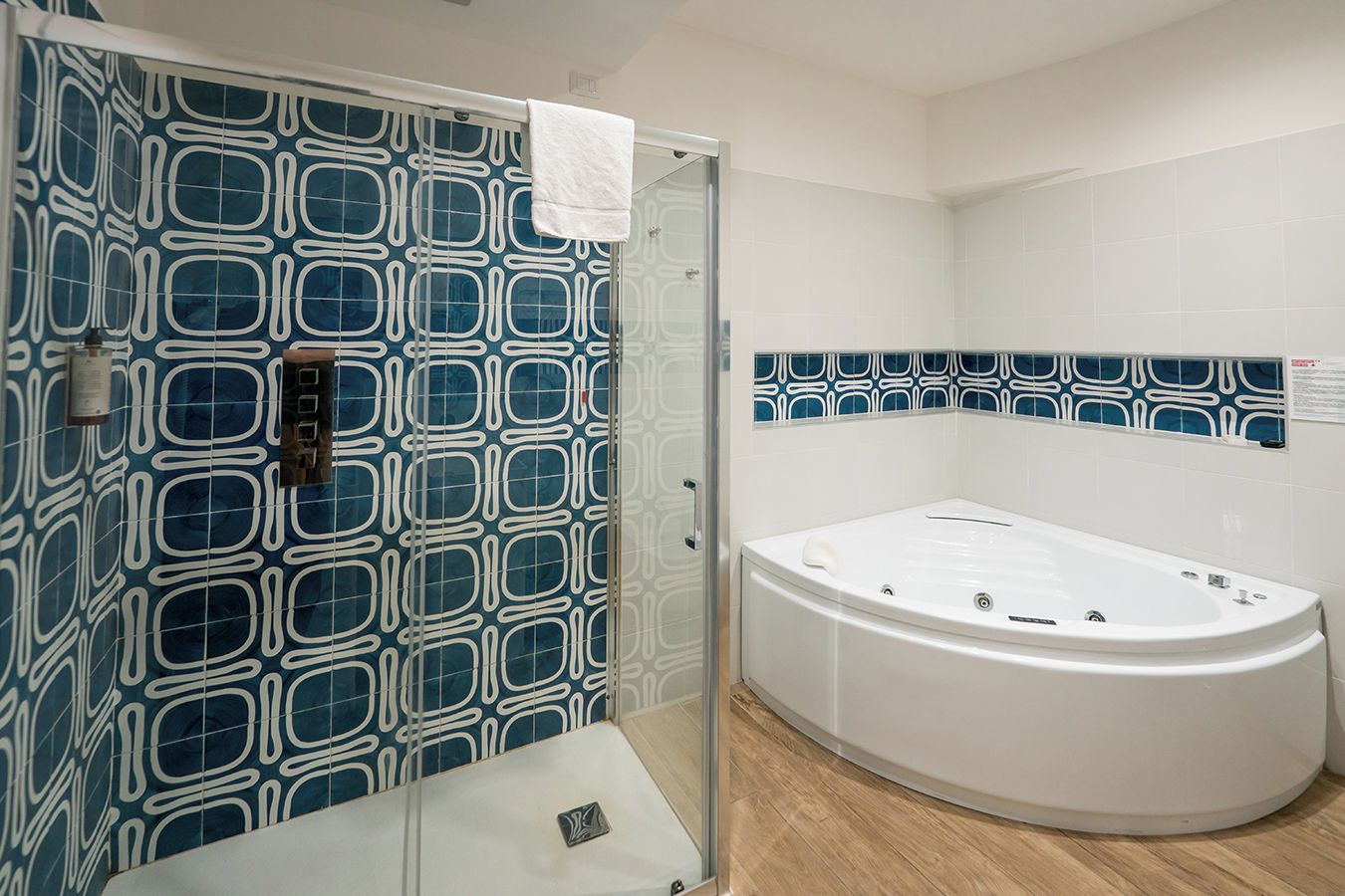 A bathroom with a large bathtub, a shower with a glass door, and patterned tiles.